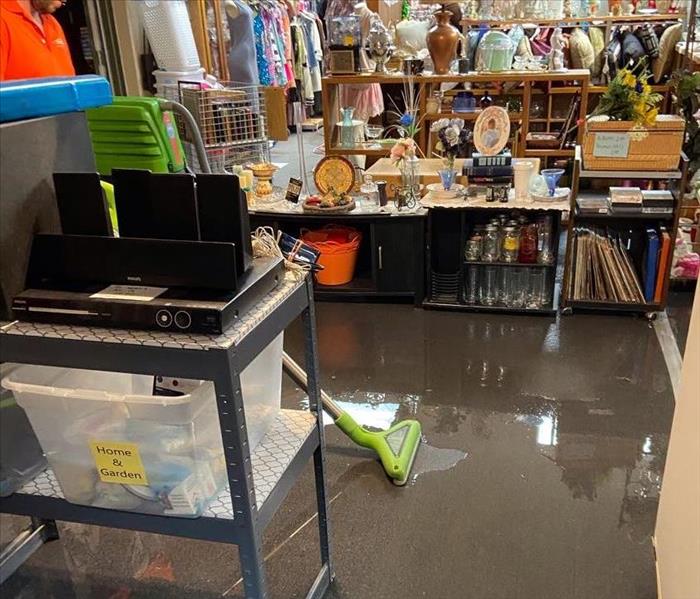 male SERVPRO employee vacuuming up standing water in clothing store