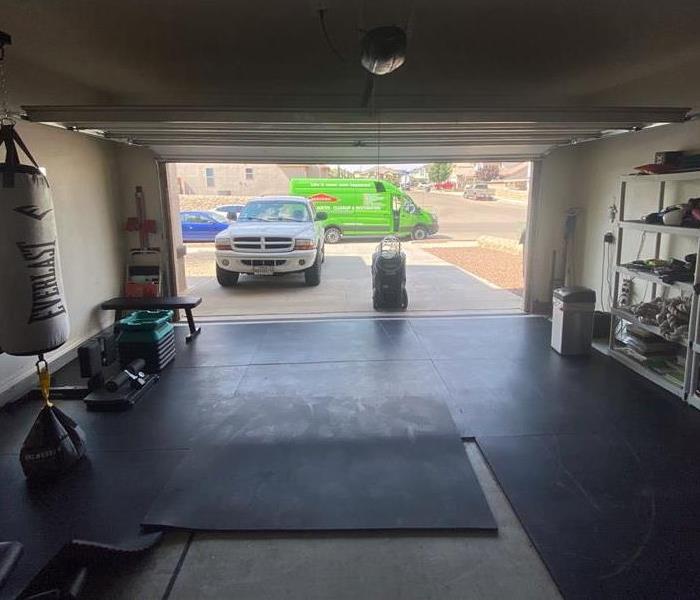 Home gym in garage with garage door open and SERVPRO truck outside