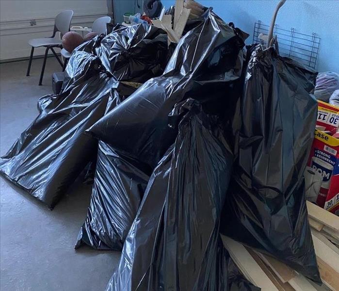 7 bags of black trash bags inside garage filled with debris