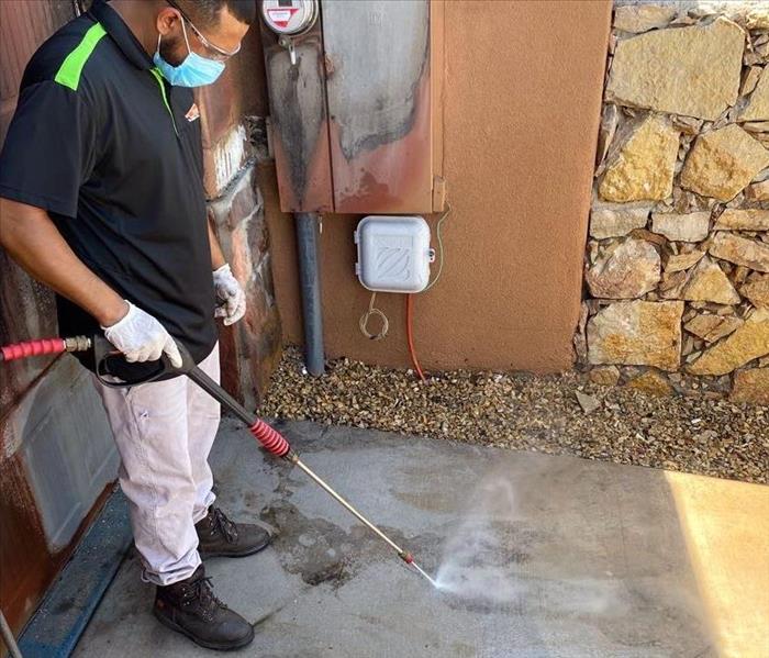 male SERVPRO employee using a pressure washer outside of home on concrete