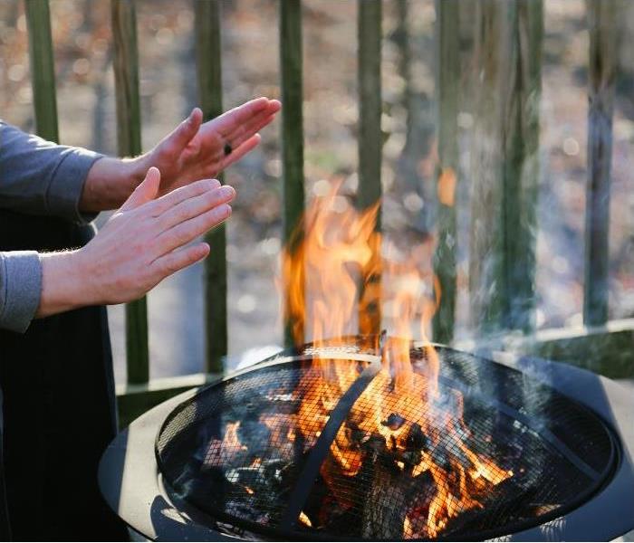 man holding hands over fire pit warming hands